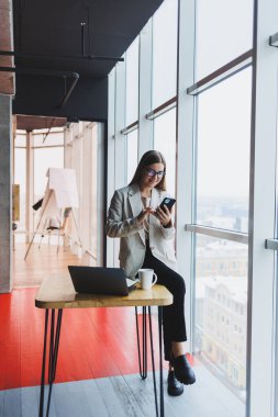 Gülümseyen kadın yönetici, kafedeki 4G kablosuz ağına bağlanan çevrimiçi uygulama üzerinden çalışmak için cep telefonu dijital aygıtı kullanıyor, neşeli serbest çalışan