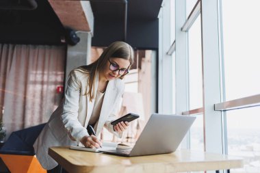 Genç ve çekici bir bayan yönetici boş zamanlarında bir kafede tek başına oturup bilgisayarla uğraşırken cep telefonuyla konuşuyor ve gülümsüyor. Mutlu kadın bir kafede dinleniyor..