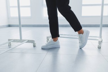 Siyah pantolonlu kadın bacakları ve beyaz deri spor ayakkabıları. Modern gündelik tarz. Yeni ayakkabı koleksiyonu