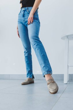 Pantolon giymiş kadın bacakları ve bej deri ayakkabılar.