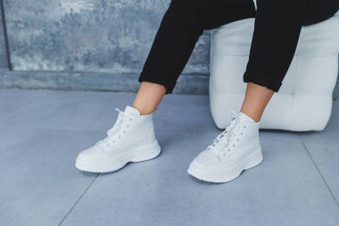 Siyah pantolonlu kadın bacakları ve beyaz deri spor ayakkabıları. Modern gündelik tarz. Yeni ayakkabı koleksiyonu