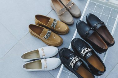 Yerde bir sürü kadın ayakkabısı, farklı deri ayakkabılar. Yeni kadın ayakkabıları yere saçılmış.