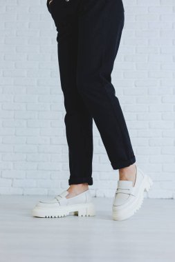 Siyah pantolonlu ve modern şık beyaz deri ayakkabılı güzel bir kadının bacakları. Yeni kadın ayakkabıları koleksiyonu bahar-yaz 2022