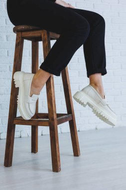 Siyah pantolonlu ve modern şık beyaz deri ayakkabılı güzel bir kadının bacakları. Yeni kadın ayakkabıları koleksiyonu bahar-yaz 2022