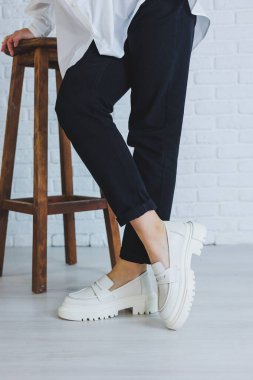 Siyah pantolonlu ve modern şık beyaz deri ayakkabılı güzel bir kadının bacakları. Yeni kadın ayakkabıları koleksiyonu bahar-yaz 2022