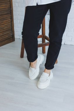 Siyah pantolonlu ve modern şık beyaz deri ayakkabılı güzel bir kadının bacakları. Yeni kadın ayakkabıları koleksiyonu bahar-yaz 2022
