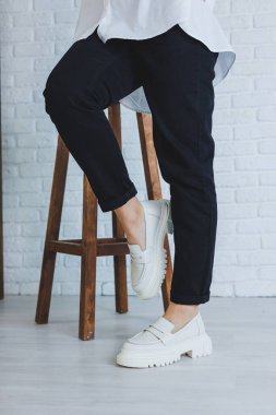 Siyah pantolonlu ve modern şık beyaz deri ayakkabılı güzel bir kadının bacakları. Yeni kadın ayakkabıları koleksiyonu bahar-yaz 2022