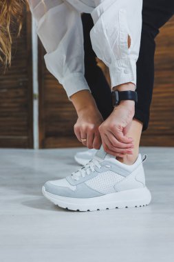 Bacaklı güzel kadın ayakkabıları, deri beyaz spor ayakkabılar, bir odanın içinde ya da ofiste, bir kadın için ayakkabılar, siyah pantolon ve beyaz spor ayakkabılar, gündelik ve modern tarz, modern ve moda