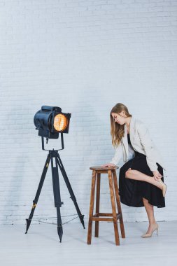 Bacağını tutan bir kadın yüksek topuklu ayakkabı giyiyor ve bacakları acıyor. Kadın siyah bir elbise ve bej yüksek topuklu ayakkabı giyiyor. Yüksek topuklardan dolayı bacak ağrısı.