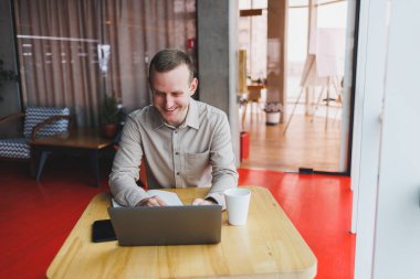 Genç bir adam online çalışırken bir masada oturup bir dizüstü bilgisayar açar. Modern dijital bilgisayar, bir kafenin içindeki bir ağ kitabında serbest yazar olarak çalışır.