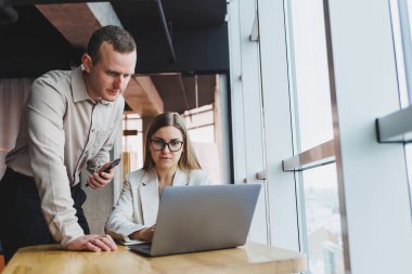 İş ortaklarıyla hızlı bir iş görüşmesi. Kendine güvenen bir grup genç iş adamı modern bir ofiste vakit geçirirken bir dizüstü bilgisayarı inceliyorlar.