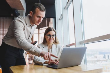 İş ortaklarıyla hızlı bir iş görüşmesi. Kendine güvenen bir grup genç iş adamı modern bir ofiste vakit geçirirken bir dizüstü bilgisayarı inceliyorlar.