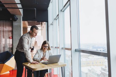 İş ortaklarıyla hızlı bir iş görüşmesi. Kendine güvenen bir grup genç iş adamı modern bir ofiste vakit geçirirken bir dizüstü bilgisayarı inceliyorlar.