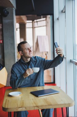 Akıllı telefonuyla internet programlama hakkında konuşan neşeli bilişim uzmanı, kafede kahve içen mutlu iş adamı. Serbest Çalışan