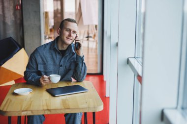 Akıllı telefonuyla internet programlama hakkında konuşan neşeli bilişim uzmanı, kafede kahve içen mutlu iş adamı. Serbest Çalışan