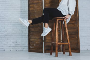 Siyah kotlu, şık, beyaz spor ayakkabılı kadın bacaklarının yakın çekimi. Yeni ayakkabılı şık bir kadın. Modern sezonluk şık spor ayakkabıları koleksiyonu. Kadın modası.