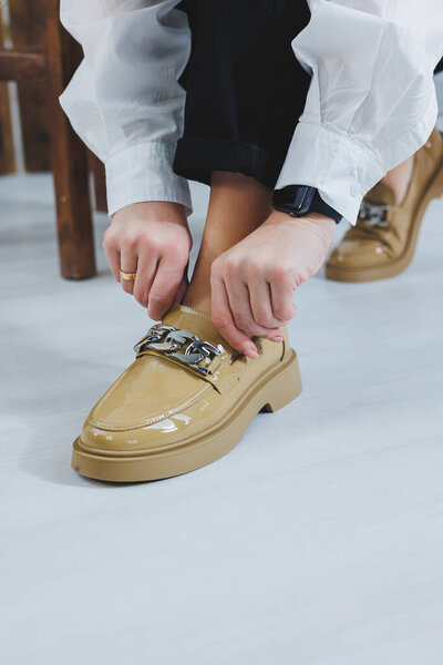 Close-up of female legs in black jeans in stylish leather beige shoes. Fashionable woman in new loafers. Modern seasonal collection of stylish shoes. Women's fashion.
