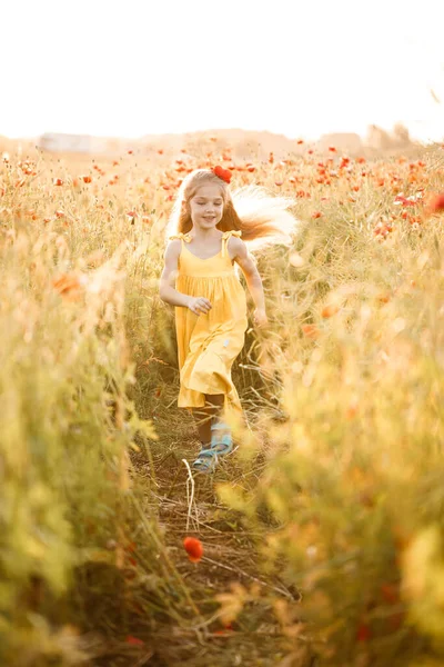 Sárga Ruhás Kislány Piros Mákvirágokkal Rohangál Zöld Hátterében — Stock Fotó
