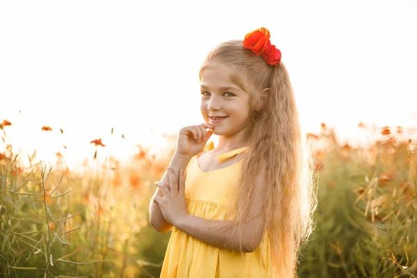 畑のポピーの中で彼女の顔に笑顔で陽気な女の子 赤い花 黄色のショートドレスと帽子のブロンド — ストック写真