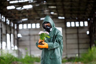 Koruyucu giysiler içinde bir dozimetrist radyasyon müfettişi ve gaz maskesi tehlike bölgesini inceliyor. Yakın plan. Çiçek. Ekolojik felaket