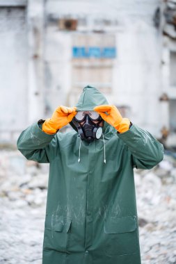 Koruyucu maskeli ve koruyucu elbiseli bir adam tehlikeli bir radyoaktif bölgeyi keşfediyor..