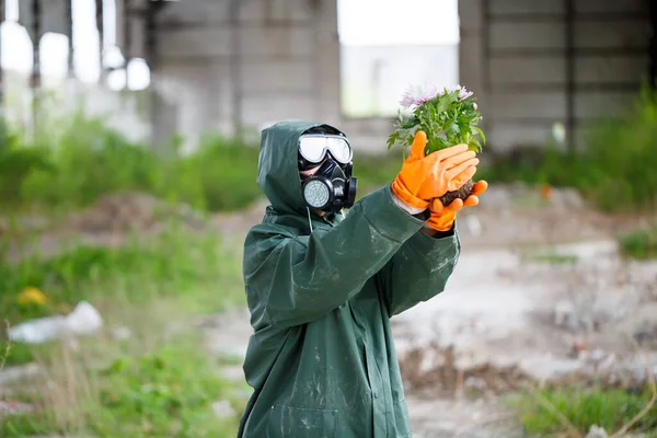 Koruyucu giysiler içinde bir dozimetrist radyasyon müfettişi ve gaz maskesi tehlike bölgesini inceliyor. Yakın plan. Çiçek. Ekolojik felaket