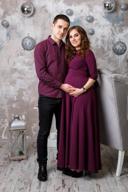 Hamile bir eşin elleri gibi ayakta duran ve karnını tutan bir koca resmi. Kadın, kız ve sevgi dolu yakışıklı adam evde karnına sarılıyor. Sevgi dolu çift. Ebeveynlik kavramı. Bebek partisi. Aile fotoğrafı..