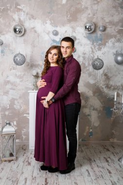 Hamile bir eşin elleri gibi ayakta duran ve karnını tutan bir koca resmi. Kadın, kız ve sevgi dolu yakışıklı adam evde karnına sarılıyor. Sevgi dolu çift. Ebeveynlik kavramı. Bebek partisi. Aile fotoğrafı..