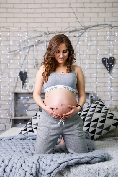 Çamaşırlı Hamile Bir Esmer Yatakta Oturmuş Karnına Bakıyor Mutlu Annelik — Stok fotoğraf