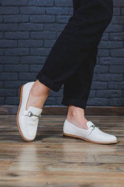 Siyah pantolon ve deri bej mokasen giyen kadın bacakları. Kadın deri ayakkabılarının yeni bahar-yaz koleksiyonu 2022