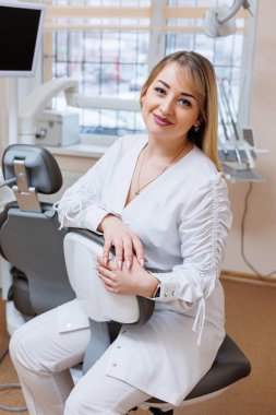 Dişçi dişçi ofisinde. Beyaz önlüklü dişçi kadın. Diş hekimliği