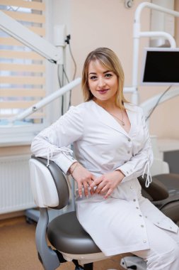 Dişçi dişçi ofisinde. Beyaz önlüklü dişçi kadın. Diş hekimliği