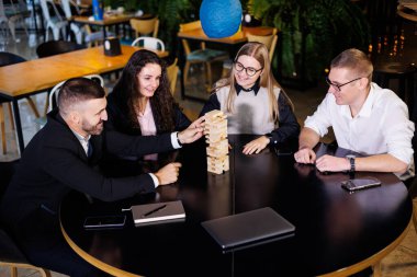 İş adamları Jenga oyunları oynuyor. Ofiste oturup oyun oynuyorlar. Tasarım ve çalışma için konsept fotoğraf.