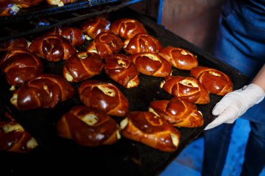 Fırıncı kız fırında bir tepsi sıcak hamur işi tutuyor. O bir kot elbise ve bir şapka giyiyor. Fırın ürünleri üretimi. Taze gevrek hamur işleriyle doldur..