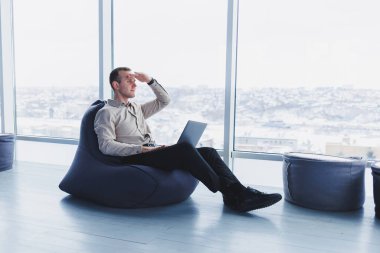 Bilgisayarlı ekrana, çevrimiçi bilgiye ya da merkez ofiste uzaktan çalışmaya odaklanmış genç işadamı, müşteri ya da çalışmayla uzaktan iletişim kuruyor.