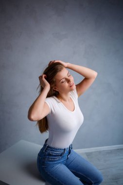 Avrupalı görünümlü sarı saçlı güzel bir kadının yakın plan portresi. Beyaz bir tişört giymişti. Bir insanın duygusal fotoğrafı.