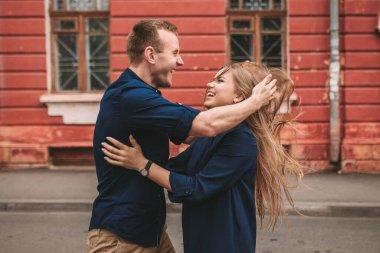 Uzun sarı saçlı, Slav görünümlü güzel bir genç kadın rüzgârda gelişiyor. O, mavi bir elbise giyiyor. Arka planda bir adam duruyor. seçici odak