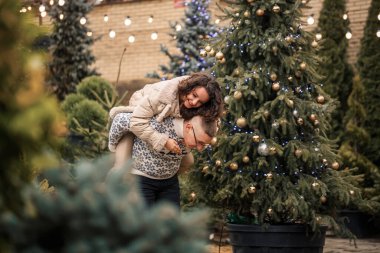 Bir kadın ve bir erkek Noel ağacının yanında duruyorlar, mutlular, yeni yıl havasında.