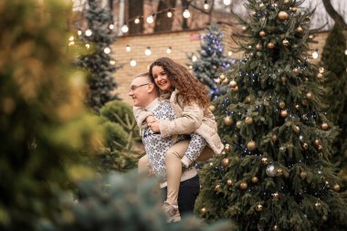 Bir kadın ve bir erkek Noel ağacının yanında duruyorlar, mutlular, yeni yıl havasında.