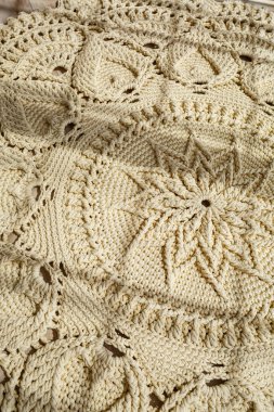 El yapımı kalın ipliklerden örülmüş ev yapımı halı: bej ipliklerden yapılmış el yapımı bir halı yerde yatıyor, güneş onun üzerinde parlıyor