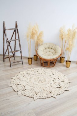 El yapımı, kalın ipliklerden yapılmış ev yapımı halı: bej ipliklerden yapılmış el yapımı halı oturma odasında, koltuğun yanında, örgü sanatının yanında yatıyor.