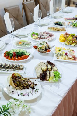 Bir restoranda şenlik masasına servis yapmak. Tatil için bir ziyafet hazırlığı. Pahalı dekorasyon malzemeleri. Yemek ve içecekler için tabaklar