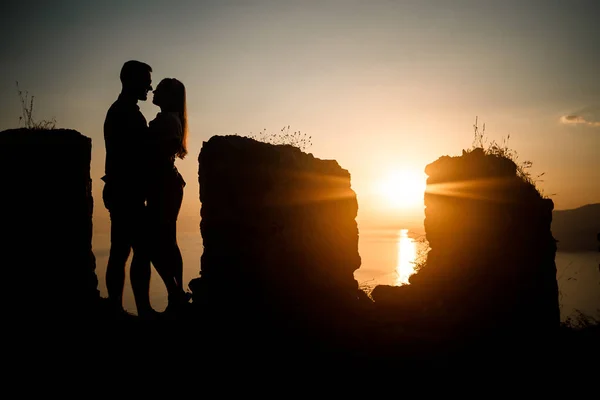 一个女人或一个男人站在岩石上 直视着海边的落日 自然与美的概念 橙色日落 日落时的轮廓 — 图库照片