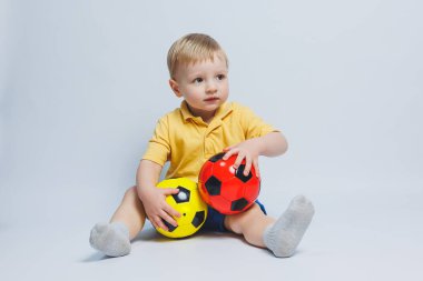 Futbol topuyla sarı ve mavi üniformalı küçük Avrupalı çocuk, fanatik ya da oyuncu, beyaz arka planda futbol takımını destekliyor. Futbol sporu, yaşam tarzı konsepti. Beyaz arkaplanda izole