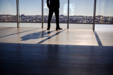 Bir adamın gölgesi büyük bir pencerenin arkasına vuruyor ve güneş vuruyor.