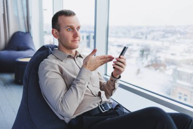 Bir iş adamı modern bir ofis çalışma alanında otururken müşterileriyle telefonla iletişim kurar. Odaklanmış iş adamı modern bir çalışma alanında tek başına oturur..