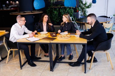 Genç tasarımcılar öğle yemeğinde ortaklarıyla yeni proje fikirlerini tartışıyor. İşadamları ofiste yeni bir iş projesini tartışıyorlar..