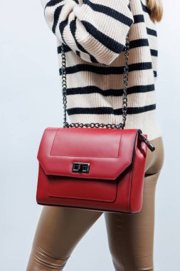 Beyaz arka planda kadın eli olan küçük kırmızı deri bir çanta. Omuz çantası. Kırmızı çantalı bir kadın. Tarz, moda, eski moda ve zarafet.