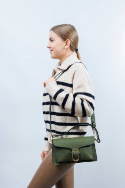 Beyaz arka planda kadın eli olan küçük, yeşil deri bir çanta. Omuz çantası. Yeşil çantalı bir kadın. Tarz, moda, eski moda ve zarafet.