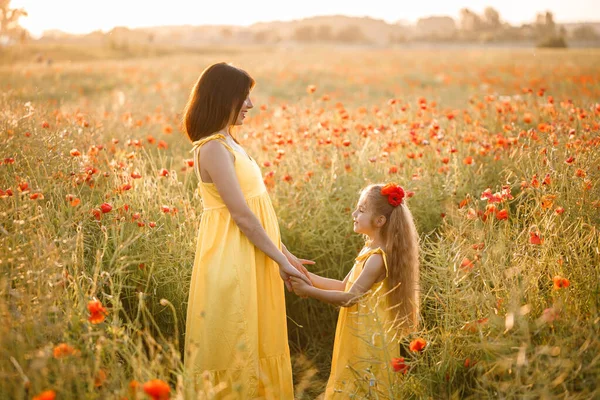 黄色のドレスを着た娘を持つ若い妊婦がケシ畑に立っている 家族関係 — ストック写真